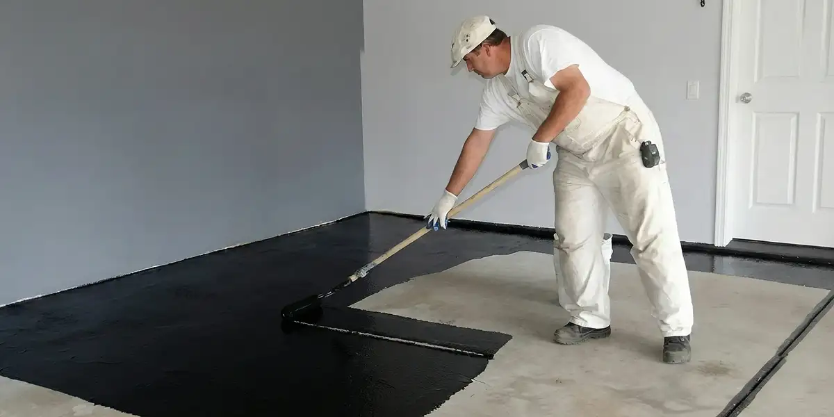 basement waterproofing professional applying waterproof coating to protect a basement floor in Grand Rapids, MI